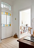 Art-nouveau-style door with stained-glass panels, view into dining room with books on sideboard