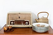 Still-life arrangement of flea-market finds; retro radio, teapot and stack of plates