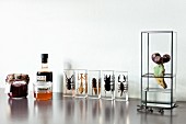 Jars of jam next to insects encased in clear resin blocks and miniature propagator on shiny surface