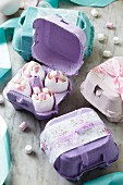 Eierschalen gefüllt mit Mini-Marshmallows in dekorativen Eierboxen