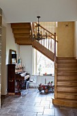 Wooden staircase in tiled hallway with antique piano and vintage-style toy car