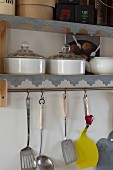 Cooking utensils hung below wall-mounted shelves with zinc edging