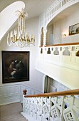 Crystal chandelier and oil painting in elegant stairwell with ornate balustrade