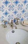 Traditional, blue and white tiles above stone washstand counter with old tap fittings and undermount sink