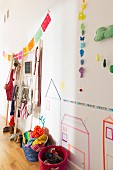 Farbige Bastkörbe mit Kinderaccessoires, Papiergirlanden und Bilder aus Masking Tape an der Wand im Kinderzimmer