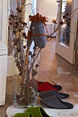 A homemade hobby horse in a vase decorated for Christmas with felt guest slippers on the floor