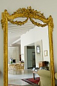 Antique mirror with ornate, gilt frame reflecting dining area