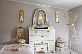 Classic, modern boudoir with white dressing table against pastel wall and vintage tailors' dummy with delicate metal frame