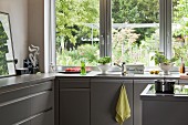 Grey L-shaped fitted kitchen with garden view
