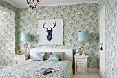 Magnolia-patterned floral wallpaper in rustic bedroom with portrait of stag above double bed