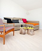Tree stump tables in front of ecru sofa next to fifties-style armchair in corner of minimalist room