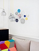 Patchwork scatter cushion below pendant lamps and decorative wall plates on wall