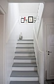 White wooden staircase with grey-painted treads in rustic stairwell