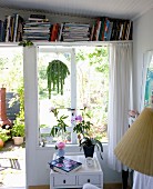 Storage solution: bookshelf above French windows with view into garden
