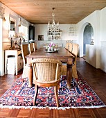 Massivholztisch mit Rattanstühlen auf orientalischem Teppich in ländlichem Esszimmer