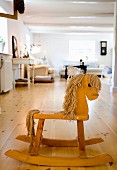 Wooden rocking horse on wooden floor in front of lounge area in rustic interior