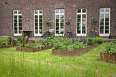 Raised beds with metal surrounds outside renovated, brick farmhouse
