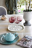 Red, smoked-glass wine glasses and teapot on dining table