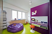 Retro stool at folding table in purple, modular kitchen and beanbag on wooden floor painted lime green