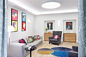 Colourful scatter cushions on grey sofa and armchair, colourful artworks on walls and round rugs on floor