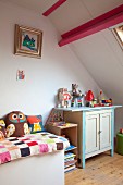 Patchwork quilt on surface and toys on rustic cabinet in child's attic bedroom