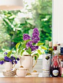 Oil bottles and nostalgic coffee set decorated with flowers on windowsill