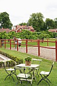 Garden table and chairs on lawn in front of horse in paddock of country estate