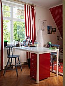White desk, red filing cabinet and red and white striped curtains in child's bedroom