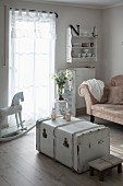 White vintage trunk, rocking horse and antique sofa in vintage-style living room
