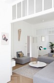 Moderne, graue Sofaelemente und elegant puristischer Coffeetable in offenem Wohnraum