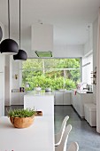 weiße, offene Küche mit grossem Fensterelement zum Garten, vorne Esstisch mit Schalenstühlen