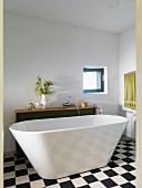 Freistehende Badewanne auf Schachbrettmusterboden in minimalistischem Bad