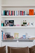 Books, photos and mementos on white custom-made shelves with modern cupboard elements