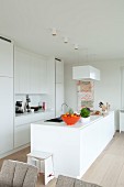 White Corian designer kitchen with island counter and orange fruit bowl