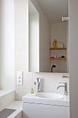 Elegant white Corian sink in niche below mirrored wall