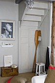 Antique wooden paddles in corner below underside of staircase and black and white photo on wall