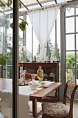 Antique furniture and floral crockery on dining table in vintage-style conservatory
