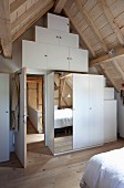 Maßgefertigter weißer Einbauschrank mit Spiegeltür in Dachgeschossschlafzimmer eines modernisierten Bauernhauses
