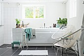 Retro Sessel mit weisser Seilverspannung neben Badewanne am Fenster, offener Duschbereich in modernem, weißem Bad