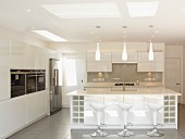 Shell-seat bar stools at sink unit in white designer kitchen