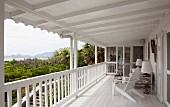 Long, white wooden veranda with view of coast and maritime-style furnishings