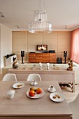 View from dining area with glass lampshade past sideboard with arrangement of ornaments to leather sofa with flatscreen TV on media cabinet