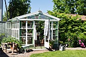 Greenhouse made from recycled materials in summery garden
