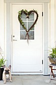Heart-shaped wreath made from birch twigs hanging on white front door