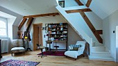 Gemütlicher Wohnraum in zweigeschossigem Dachraum mit gewendelte Holztreppe, weiss lackiert