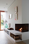 Fire in open fireplace and low sideboard integrated into wall