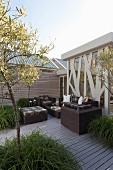 Trees in large planters and modern, dark wicker outdoor furniture on wooden terrace
