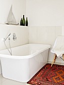 White, free-standing bathtub in bright bathroom with rug