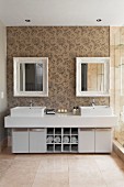 Twin washstand with square basins in elegant bathroom with ornamental wallpaper