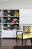 Yellow armchair in front of white shelving brightened up by decorative adhesive film on back wall